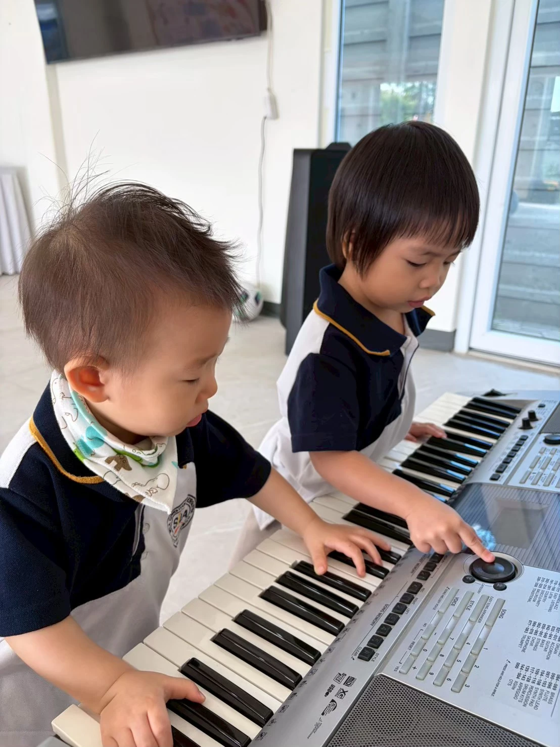 Two children playing a keyboard together during Piano