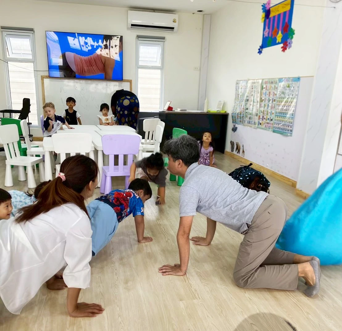 孩子和大人们在共同的运动活动中一起在教室地板上爬行
