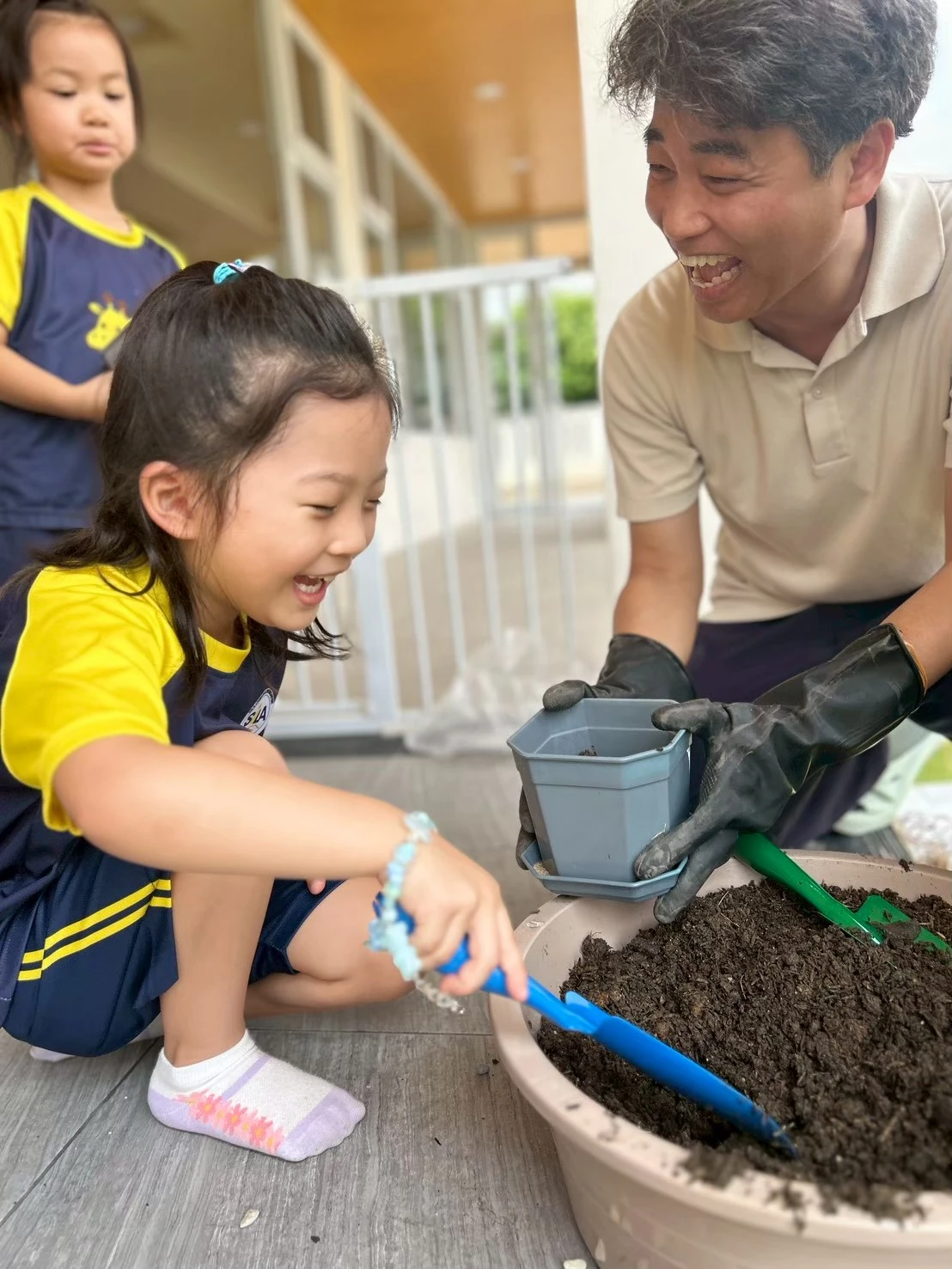 老师和孩子一起种植物，开心地笑着