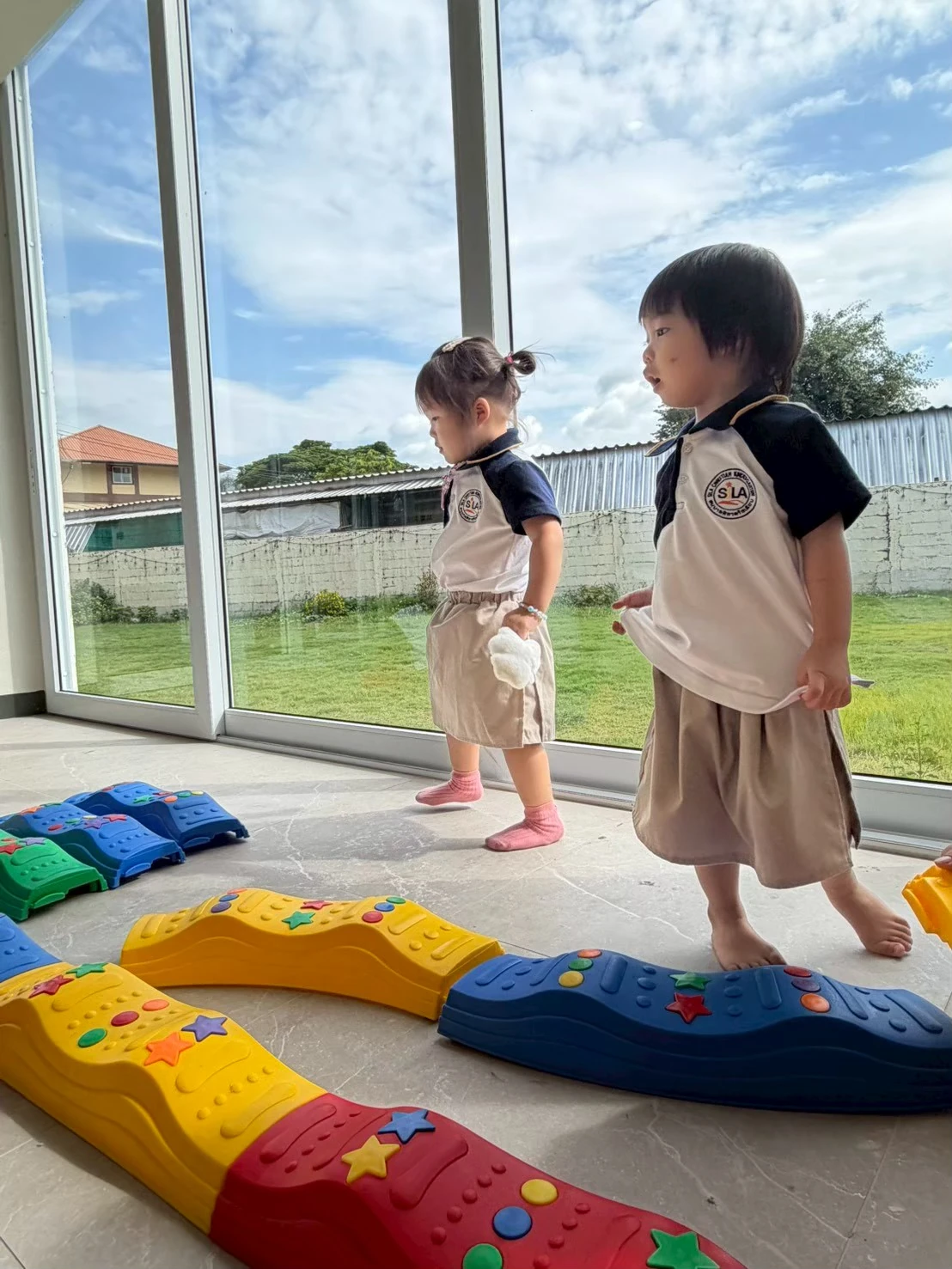两个年幼的孩子在阳光明亮的教室里一起走过感官平衡步道