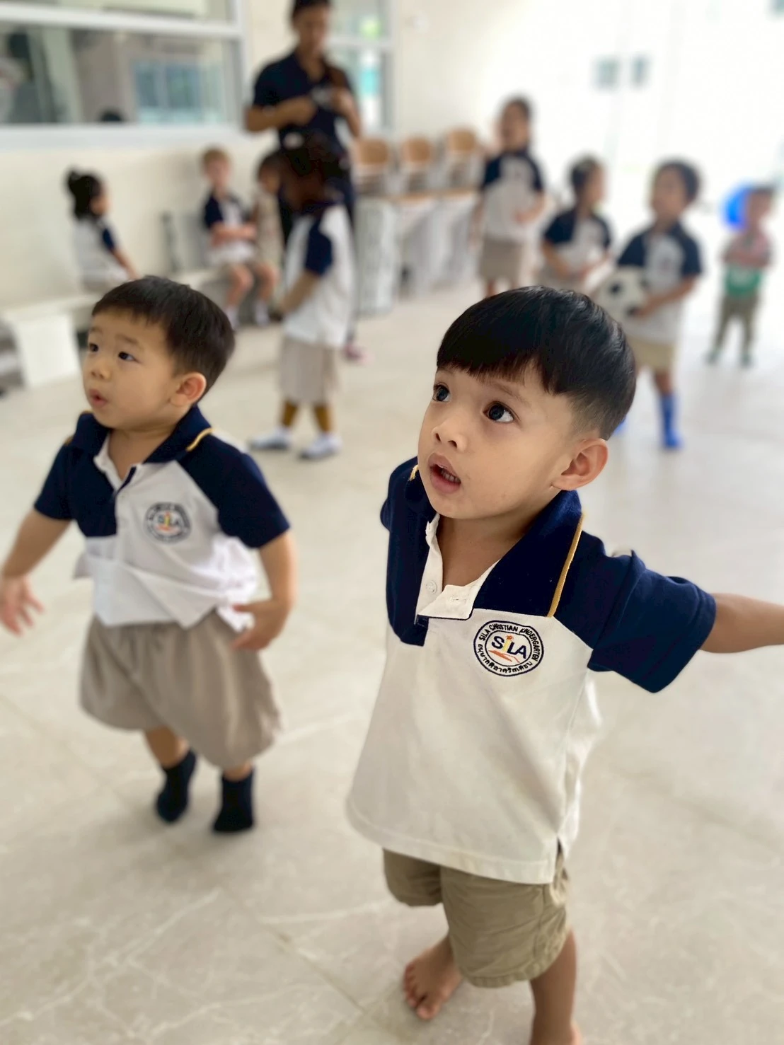 两个 Nursery 男孩一起走过明亮的室内游戏空间，抬头张望